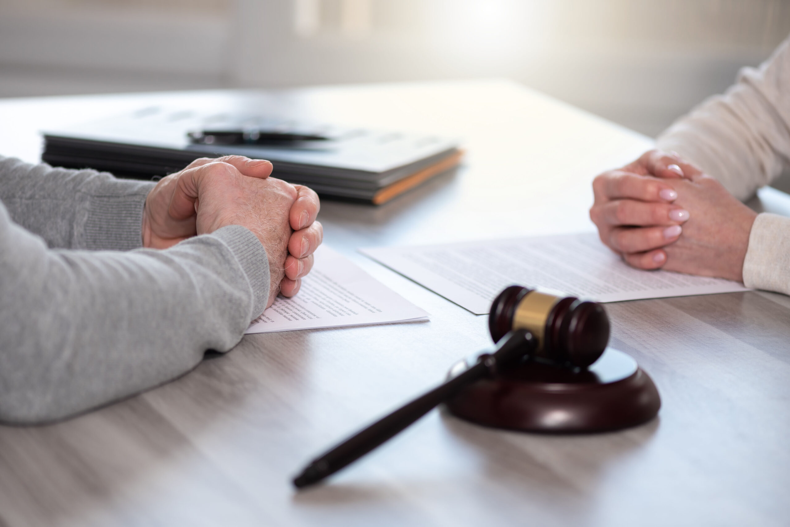 Hands of couple sitting face to face. Concept of divorce with judge gavel