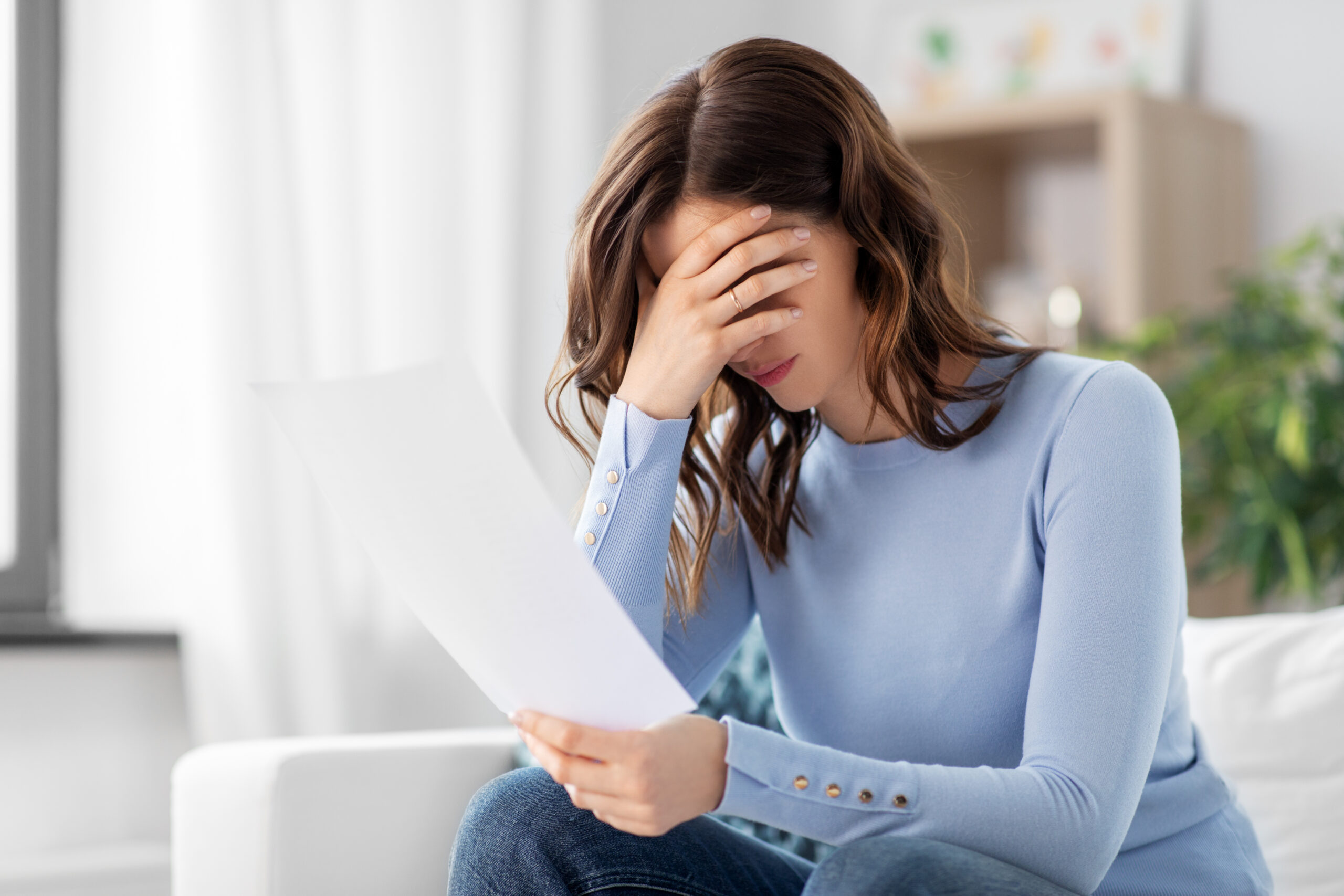 stressed woman with paper sheet at home